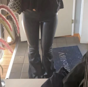 Skinnbyxor - Säljer ett par svarta byxor i skinnimitation med bootcut-modell. Byxorna har en tight passform upptill och utsvängda ben nertill, vilket ger en snygg siluett. Perfekta för dig som vill ha en trendig och edgy look.
