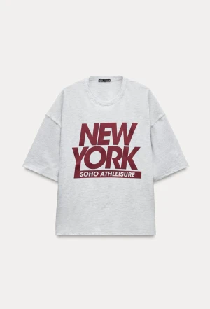 Grå  t-shirt med New York-tryck - Säljer en grå t-shirt från Zara med stort vinrött New York-tryck på bröstet. T-shirten har korta ärmar och en loose passform, perfekt för dig som gillar streetstyle och sportig vibe. Materialet är mjuk bomull som känns skönt mot huden.
