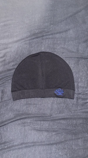 Syna world mössa  - En jätte fin mössa som är bra inför vintern och har en jätte snygg och skön marin blå logga på den. Den hära svarta mössan passar med mycket och håller dig ganska varm under vintern.