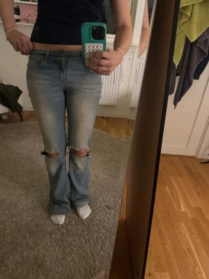 Ljusblå bootcut jeans med hål - Ljusblå jeans från Nelly med slitna hål över knäna och snyggt tvättad look. Modellen är bootcut med låg midja och raka ben som blir vidare nertill. Klassisk femficksdesign och tillverkade i mjukt jeanstyg. Perfekta för en avslappnad och trendig stil. Dom är också slitna vid änden av byxorna pga skor som har råkat gå på kanten! 
