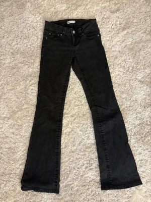 Svarta bootcut jeans från Gina Tricot - Snygga svarta jeans från Gina Tricot i modellen Perfect Jeans, storlek 34. Bootcut passform med klassiska fem fickor och coola detaljer på bakfickorna. Jeansen har normal midja och är tillverkade i stretchigt denim för skön passform.