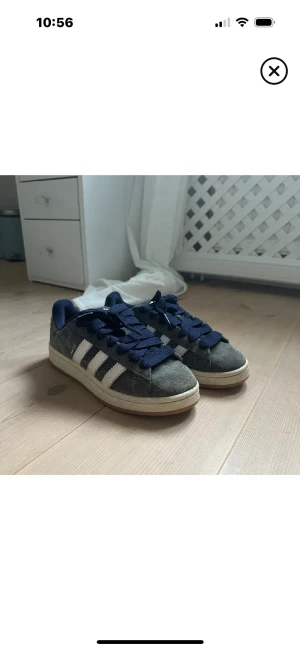 Adidas Campus sneakers mörkblå  - Säljer ett par Adidas Campus sneakers i mörkblå mocka med klassiska vita ränder på sidorna och mörkblå snören. Skorna har en rund tå och platt sula, samt en beige kant runt sulan. 
