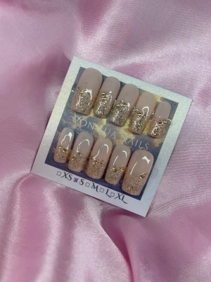 Glam (S);Medium Square;Curved - Snygga handgjorda press-on naglar i nude med guldglittrig tipp och små guldfärgade stenar. Naglarna har en rak, medium square design och en glansig finish. Perfekt för dig som vill ha en lyxig look utan att gå till salong.S: 15 mm, 11,5 mm, 12 mm, 11 mm, 9 mm 