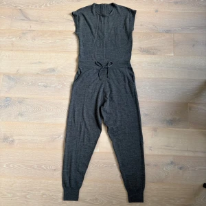 Ny skick MO&Co. jumpsuit - Säljer en jumpsuit från MO&Co. i nästan nyskick.
 Tyget är mycket fint och följsamt, känns supermjukt mot huden och håller hög kvalitet.
 Designen är stilren och välgjord med skärpning i midjan och ett midjeband/snöre för justering. På baksidan finns en dragkedja med säkerhetsknapp för bättre passform och trygg förslutning.
 Material: 50.6 % ull, 49.4 % akryl
 Storlek: M (160/84A) 
 Perfekt för både vardag och arbete – en bekväm, elegant och lättmatchad one-piece.
 Tillgänglig för upphämtning i Kista,