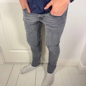 Dondup jeans George skinny fit grå - Dondup jeans George skinny fit, inga direkta defekter. Väldigt fint skick, modellen är 180 cm 75 kg och bär storlek W33 . Mått A: 40 cm B: 99 cm och väldigt stretchy. Dom är inte så skinny i verkligheten utan bara vinkeln bilden är taggen. Notera att måtten kan skilja någon centimeter beroende hur man mäter. Jeansen är väldigt hög kvalité, och är riktigt snygga! Kom med frågor ❤️