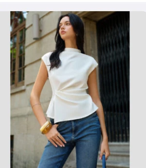 Tag On! Never worn - Säljer en stilren vit blus med omlottdetalj i midjan och korta ärmar. Toppen har en lätt A-linjeformad siluett och hög halsringning, vilket ger en modern och fräsch look. Perfekt att matcha med jeans eller kjol för en trendig outfit.