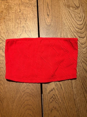Röd bandeau tubtopp från SHEIN SXY - Säljer en röd bandeau tubtopp från SHEIN SXY i storlek XS. Toppen är axelbandslös och har en lätt ribbad struktur i tyget som ger en cool look. Perfekt för dig som gillar att sticka ut med färg. Materialet är mjukt och stretchigt.