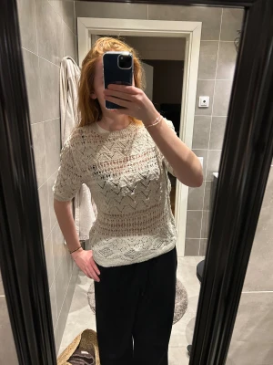 Vit stickad blus från Zara - Säljer en vit stickad blus från Zara i storlek M. Toppen har korta ärmar, rund halsringning och ett genombrutet, mönstrat stickat material med snygga detaljer. Perfekt för dig som gillar en luftig och trendig look.