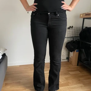 Svarta bootcut jeans från Gina Tricot - Säljer ett par svarta bootcut jeans från Gina Tricot, modell Perfect Jeans. De har klassisk femficksdesign, snygga bakfickor med lock och silverfärgade knappar. Jeansen är i stretchig bomullsblandning och har normal/låg midja. För ref är jag cirka 170 cm lång och byxorna slutar ca 1cm ovanför hälen. Skriv för fler frågor!🫰🏼