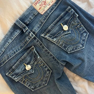 Blå true religion bootcut jeans Low waist joey - Säljer ett par klassiska blå jeans från True Religion med bootcut passform i nästan helt nytt skick använda några få gånger och lite slitna ner vid hälarna som syns på en av bilderna dom är i storlek 23 men jag har storlek 24 i alla mina jeans och dom passar mig jättebra köpte dom för 1300 och som sagt har jag bara använt dom några gånger.💕💕