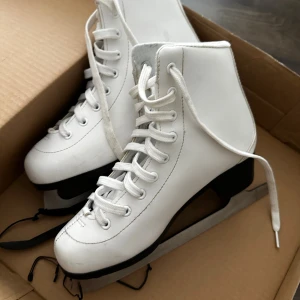 Vita konståkningsskridskor strl 37 - Säljer ett par klassiska vita konståkningsskridskor i storlek 37. De har högt skaft, snörning och svart klack. Yttermaterialet är syntet och skridskorna har en stilren look som passar perfekt för isbanan.