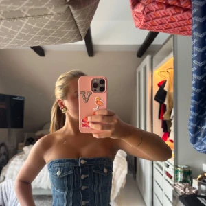 Jeans korsettopp från Zara - Säljer en snygg jeans korsettopp från Zara i mörkblå denim. Toppen är axelbandslös, har silverfärgade knappar framtill, två fejkade bröstfickor och rå kant nertill för en edgy vibe. Perfekt att styla med vida byxor eller kjol.