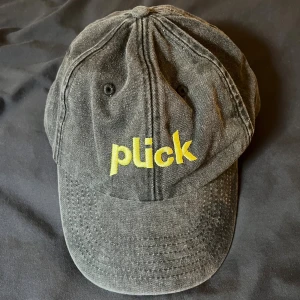 Svart keps med gul Plick-logga - Cool svart keps från Plick i 100% bomull med broderad gul logga framtill. 