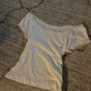 Vit  topp med spetskant - Supersöt vit offshoulder topp med korta ärmar och spetsdetaljer längs halsringning och ärmslut. 