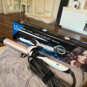 LSA Jumbo Curl Hair Curler 38mm - Stor locktång från Lesasha med 38mm fat, perfekt för att skapa stora, mjuka lockar. Tången är i skimrande ljusrosa och vitt med svarta detaljer och lång sladd. Ergonomiskt handtag och digitala knappar för enkel användning.
