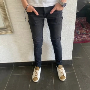 Tiger of Sweden Jeans - Svarta slim fit jeans med klassisk femficksdesign och diskret svart patch bak i midjan. Jeansen har smal passform hela vägen ner och är tillverkade i ett stretchigt denimtyg för en snygg och bekväm look.