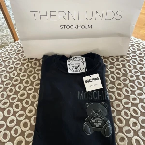 Svart Moschino t-shirt med björn - Svart t-shirt från Moschino med ikonisk björn. Klassisk passform, rund hals och korta ärmar. Köpt på Thernlunds och är 100% äkta, vid mer frågor och bilder är det bara att skriva!