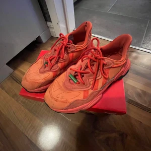 Röda sneakers från Puma - Säljer ett par feta röda Puma sneakers med chunky svart sula och coola detaljer i mocka och syntet. Skorna har snörning med gröna detaljer och en sportig vibe. Perfekta för dig som vill sticka ut med färg och stil.