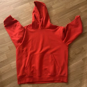Röd hoodie med huva och ficka - Snygg röd hoodie med stor huva och klassisk magficka. Tröjan har långa ärmar och en relaxed passform, perfekt för chill dagar. Tillverkad i mjukt material som känns skönt mot huden.