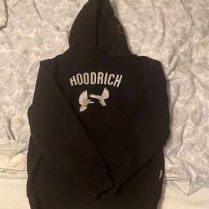 Svart hoodie från Hoodrich med tryck - Svart hoodie från Hoodrich med stor vit text och duvor på ryggen. På bröstet finns ett tryck med röda bokstäver 'From Nothing To Something' och vita duvor. Klassisk huva och känguruficka. Perfekt streetwear-vibe. Jag är 170 och den passar mig bra. Skriv för frågor!