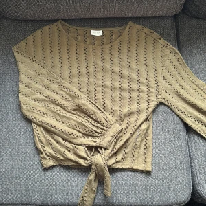 Militärgrön knytblus från Vila storlek xs - Militärgrön blus från Vila i storlek XS. Blusen har långa ärmar med ”håligt” mönster och knyt framtill. Använd flitigt med inga defekter.