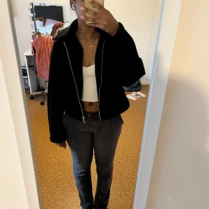 Svart teddyjacka från VILA - Mysig svart teddyjacka från VILA i storlek 36. Jackan har en cool krage, dragkedja framtill och är tillverkad i fluffigt teddy-material som ger en chill vibe. Perfekt för att hålla sig varm och ändå se stylish ut. Passar dig som gillar en loose fit och enkel design.