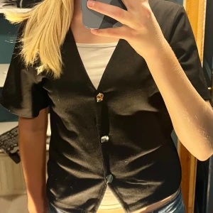 Svart kortärmad blus - Svart blus från laget 157 med v-ringning. Använd max fem gånger. Säljes då den inte används. 