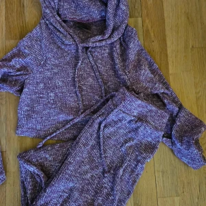 Lila stickad hoodie och byxor från Gymshark S - Supermjuk och cozy lila stickad hoodie från Gymshark med snörning i huvan och croppad passform. Perfekt för chill dagar eller när du vill vara extra bekväm. Matchande byxor finns också om du vill köra hela setet.