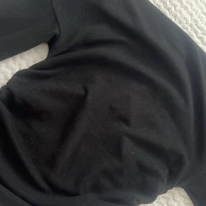 Svart sammetströja med rynkning i midjan  - Säljer en svart sammetströja med snygga rynkade detaljer längs midjan. Tröjan har lång ärm och är i ett mjukt, lyxigt material som känns riktigt skönt mot huden. Perfekt för dig som gillar en stilren look med en twist.