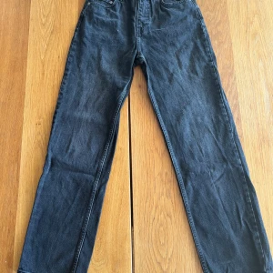 Svarta raka jeans från NA-KD - Snygga svarta jeans från NA-KD med klassisk femficksdesign och raka ben. Jeansen har hög midja och är tillverkade i ett mjukt bomullsmaterial med lite stretch för extra komfort. Perfekta för en clean och stilren look.