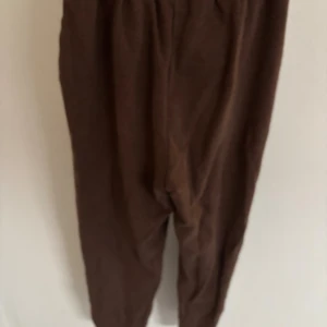 Bruna mjukisbyxor från Gymshark XS - Mysiga bruna mjukisbyxor från Gymshark i storlek XS. Byxorna har dragsko i midjan, sidofickor och en liten Gymshark-logga på benet. Perfekta för chill eller träning, i mjukt material och relaxed fit. Passar s och m. Dessa mjukis är slusålda och collektionen kommer intr tbx 