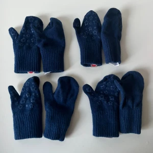 Mörkblå tumvantar - Säljer fyra par mörkblå vantar från PAX med snyggt stjärnmönster på ovansidan. Vantarna är stickade och tillverkade av akryl, ull, polyester och elastan.