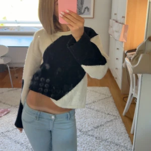 Svartvit stickad tröja från Gina Tricot - Säljer en snygg stickad tröja från Gina Tricot i svart och vitt med coolt grafiskt mönster. Tröjan är croppad, har lång ärm.