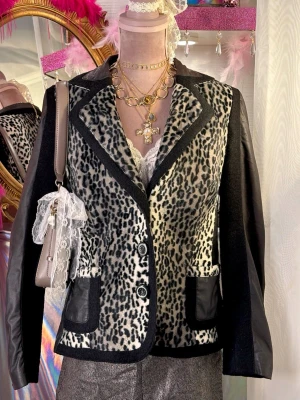 Animal Print Leopardmönstrad kavaj/ jacka i ullblandning  - Unik vintagejacka i leopardmönstrad fuskpäls med ärmar i läderimitation och ull detailjer. Bra statement piece!  • Brand: Adagio • Storlek: passar S/M • Skick: Bra vintageskick  Notering: Detta är en vintagejacka av fin kvalitet med mycket liv kvar! Notera dock att det finns mindre slitage/märken samt viss blekning på de svarta partierna (se bilder för detaljer).