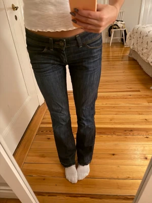 Mörkblå jeans från Wrangler - Säljer ett par mörkblå snygga jeans från Wrangler. Jeansen har låg midja med en bootcut passform. Materialet är jeans och de var även snygga detaljer som till exempel på bakfickan💞💞