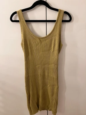 Ribbad beige kortklänning från H&M - Supersnygg ribbad kortklänning från H&M i beige ton. Klänningen är ärmlös med rundad urringning och har en figurnära passform. Stickad struktur. Storlek L men skulle säga mer som en S-M