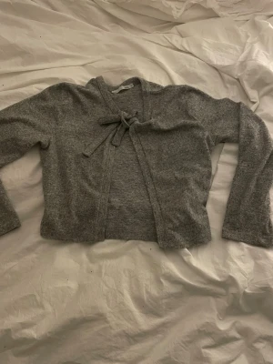 Grå kofta med knyt från 157 - Säljer en söt grå kofta från lager 157 men knyte framtill. Storlek S💓 Jag säljer då den inte kommer till användning längre. 💓