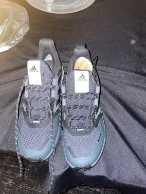 Adidas Terrex svarta sneakers Gore-Tex - Säljer ett par svarta och grå Adidas Terrex sneakers med Gore-Tex-material. Skorna har snörning, mesh- och syntetdetaljer samt grov sula för extra grepp. Perfekta för dig som gillar att vara aktiv utomhus och vill ha stilrena skor med funktion.