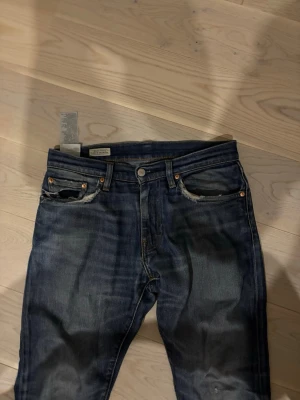Levis 511 mörkblå skinny jeans - Mörkblå Levis 511 jeans med skinny passform och klassisk femficksdesign. Jeansen har slitningar vid fickorna och är tillverkade i tåligt jeansmaterial. Snygg tvätt med lätt slitna detaljer för en avslappnad look.