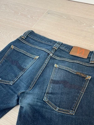 Nudie Jeans, Grim Tim 30/34 - Säljer ett par mörkblå jeans från Nudie Jeans. I storlek W30 L34. Jeansen är i ett mycket bra skick. Fraktar inom 24h, bör gärna av er vid frågor!🤗