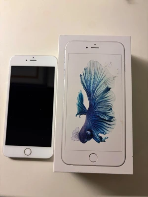 iPhone 6s Plus 16GB Silver - Apple iPhone 6s Plus i silver med 16GB lagring. Telefonen levereras med originalkartong. Skärmen är felfri, men baksidan visar mindre tecken på slitage, men f ö fint skick. Perfekt för dig som söker en pålitlig och klassisk iPhone-modell med stor skärm. Batterihälsa vet jag tyvärr inte, mem mest legat i en låda så nog hyfsad:)