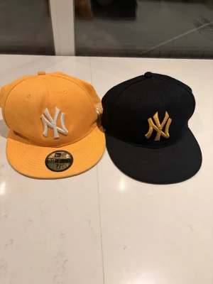 Gul och svart New Era Yankees keps - Två feta New Era 59FIFTY Yankees kepsar säljes dem är i ganska bra skick och har använts i 3 månader gula kepsen har size 59,6cm och svarta har 55,9cm jag säljer dem en och en fast om du vill köpa dem som ett pack skriv privat och säg det så får du förbättrat pris!!