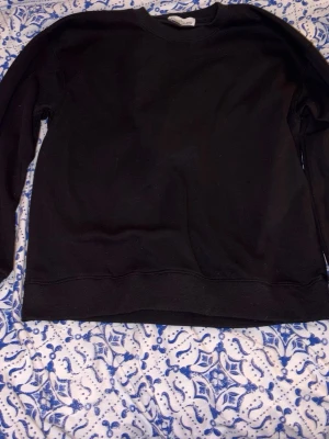 Svart sweatshirt från Stone Island (sitter som M) - Klassisk svart sweatshirt från Stone Island i storlek S. Tröjan har rund hals, långa ärmar och den ikoniska Stone Island-patchen på ärmen. Tillverkad i mjuk bomull för skön känsla och stilren look. Den sitter som M