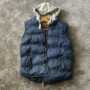 Mörkblå dunväst med grå huva Cedarwood State - Snygg mörkblå dunväst från Cedarwood State i storlek M. Västen har även en grå luva som är skit snygg och passar perfekt till outfits