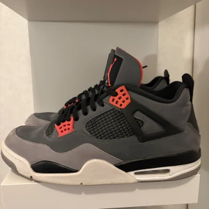 Nike Air Jordan 4 Retro Grå/Röd - Nike Air Jordan 4 Retro sneakers i grå mocka med svarta och röda detaljer. Priset går att diskutera då jag försöker att bli av med så mycket kläder som möjligt.