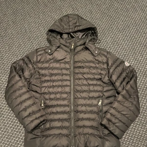 Svart Moncler dunjacka med huva - Säljer en svart dunjacka med avtagbar huva och dragkedja framtill. Perfekt för kalla dagar.  OBS REp