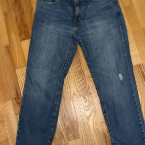 Levi's 541 blå jeans W33 L30 - Säljer ett par klassiska Levi's 541 jeans i blå tvätt med raka ben och fem fickor. Jeansen har en normal passform och är tillverkade i slitstarkt denim. Perfekt för dig som gillar en tidlös look och vill ha ett par jeans som funkar till det mesta.