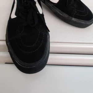 Svarta Vans Old Skool sneakers - Säljer ett par klassiska Vans Old Skool sneakers i svart mocka och canvas med vit sidorand. Skorna har snörning och en platt, mönstrad gummisula som ger bra grepp. Perfekt för dig som gillar streetstyle och skate-vibe.