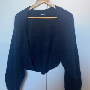 Svart stickad kofta från Gina Tricot - Mysig svart stickad kofta från Gina Tricot med lång ärm och öppen front. Koftan har en loose passform och är perfekt att slänga på sig över en t-shirt eller linne. Enkel och stilren design som funkar till många outfits.