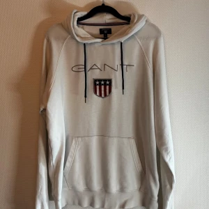 Vit hoodie från GANT  - Säljer en vit hoodie från GANT i storlek L, storleken är inte L enligt mig. Passar bättre till S/M. (Ser grå ut på bilden men den är mycket vitare i verkligheten) Hör av er vid frågor!